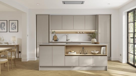 A cream, sandstone kitchen in a gloss finish and handlelss cabinets. It has light oak flooring, with a kitchen island. 