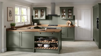 A shaker kitchen in a dark ash green colour and a peninsula layout. There is matching wall panelling and pale oak worktops.