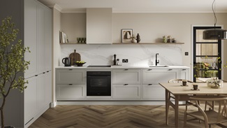 A white, pebble shaker kitchen with in-frame detail. It is in an l-shaped layout with marble-effect worktops & splashback.