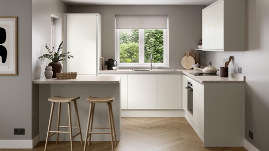 A white, porcelain kitchen with handleless fronts. It is in an l-shaped layout with a breakfast bar and oak-effect flooring.
