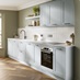 A mist-blue shaker kitchen with in-frame detailing. It is in a single-wall layout and has warm oak herringbone flooring.