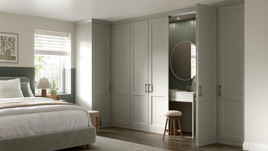Bedroom with shaker-style fronts in a light pebble colour. Behind one door is a dresser unit with matching door and mirror.