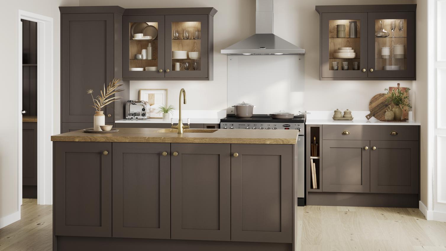 A truffle brown kitchen in a shaker style and peninsula layout. It has wood worktops, brass accessories, and glass cabinets.