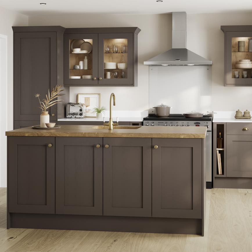 A truffle brown kitchen in a shaker style and peninsula layout. It has wood worktops, brass accessories, and glass cabinets.