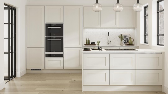 A handleless cream shaker kitchen with silver trims in a peninsula layout. Contains a black microwave and a warming drawer.