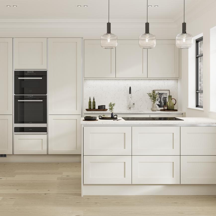 A handleless cream shaker kitchen with silver trims in a peninsula layout. Contains a black microwave and a warming drawer.