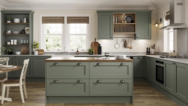 A reed green shaker kitchen idea in an island layout, with dark oak worktops, chrome handles, oak floors, and a plate rack.
