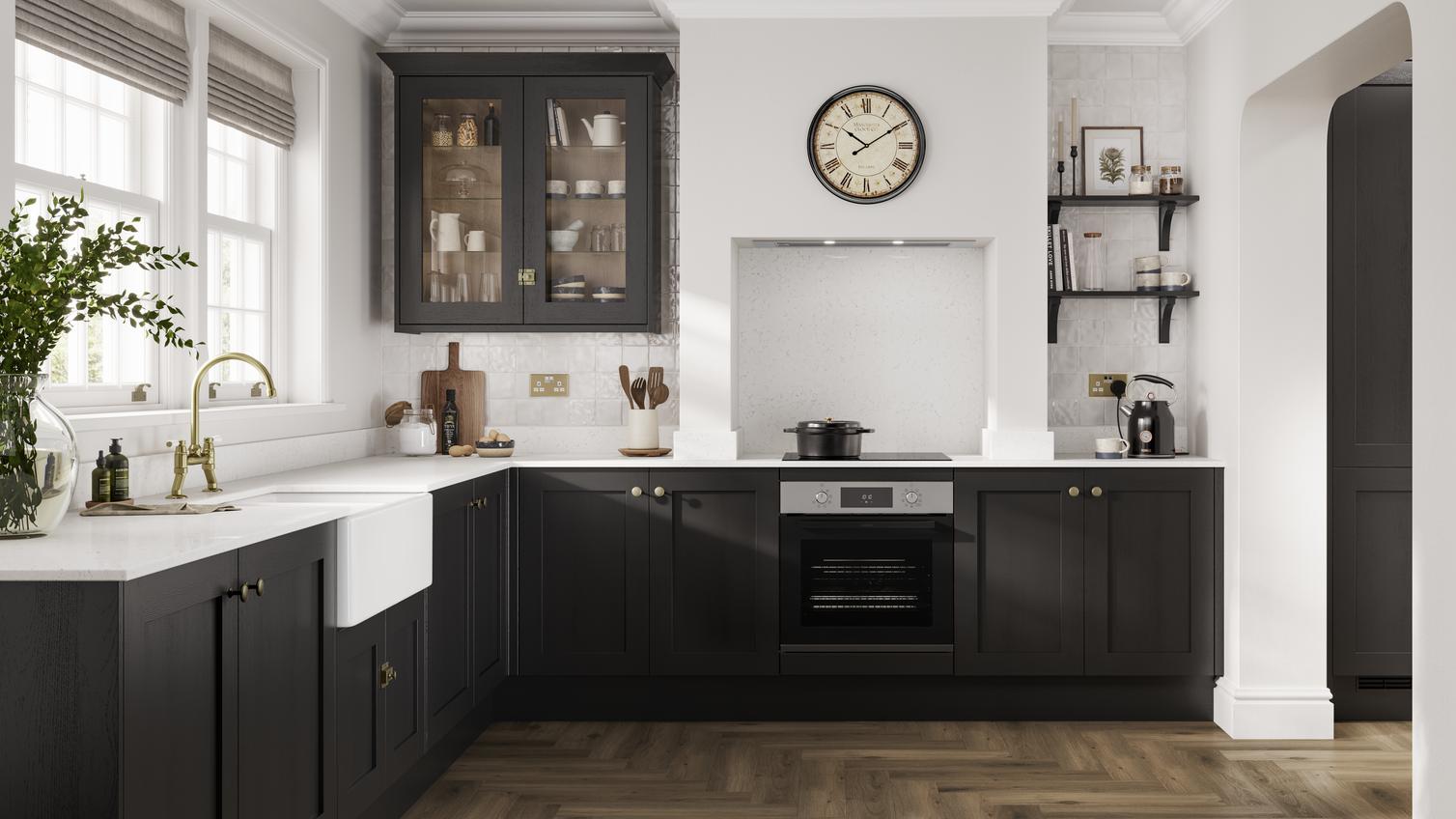 A black shaker kitchen in an L-shaped layout. There are white worktops, chevron oak laminate flooring and a Belfast sink.