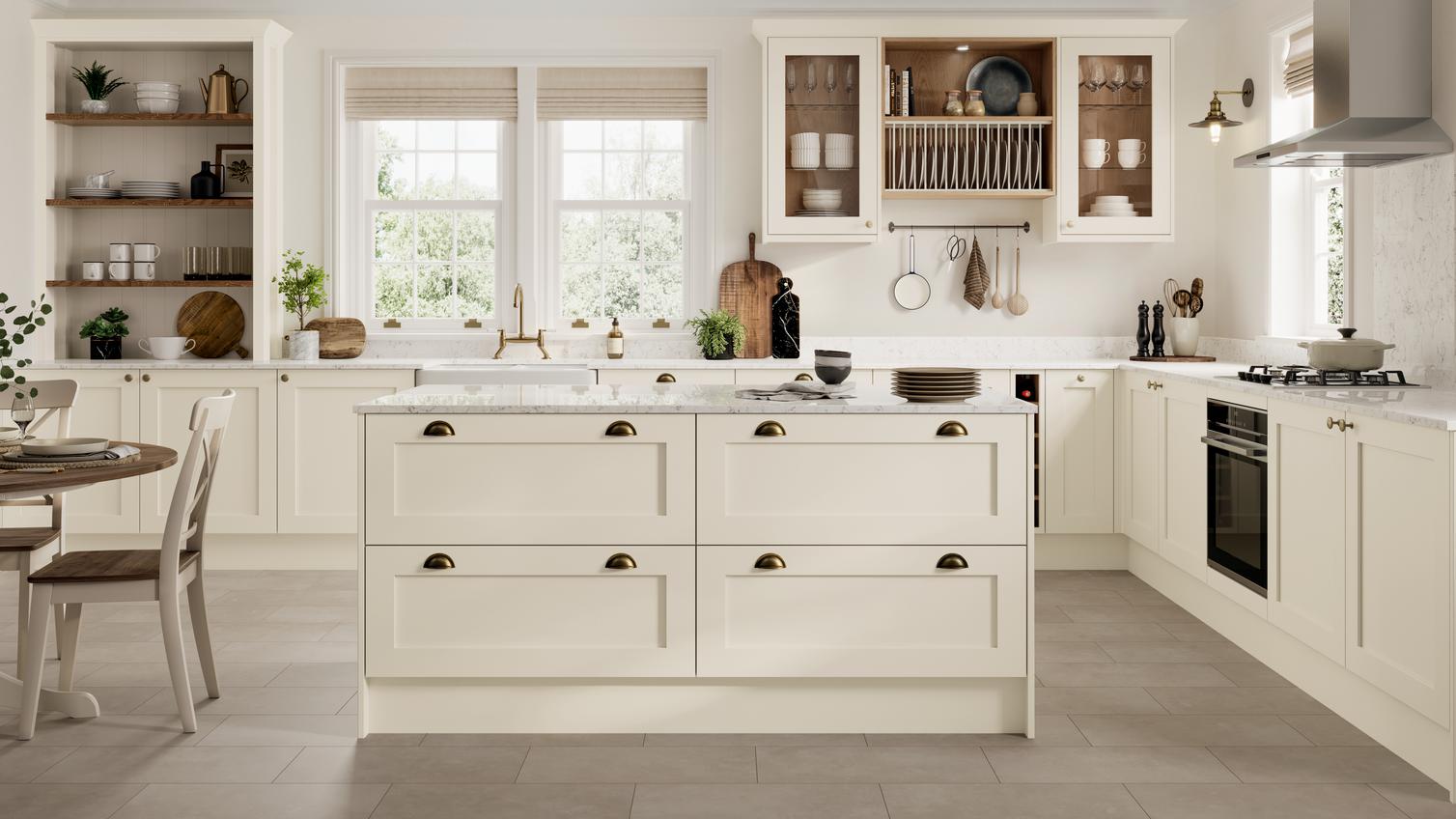 A cream-coloured, Linen shaker kitchen in an island layout. It has brass accessories, quartz worktop, and tile flooring.