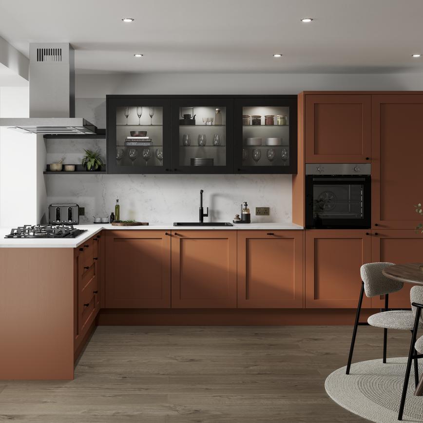 A paprika orange shaker kitchen in an L-shaped layout. There are white worktops and glass cabinets with black frames.