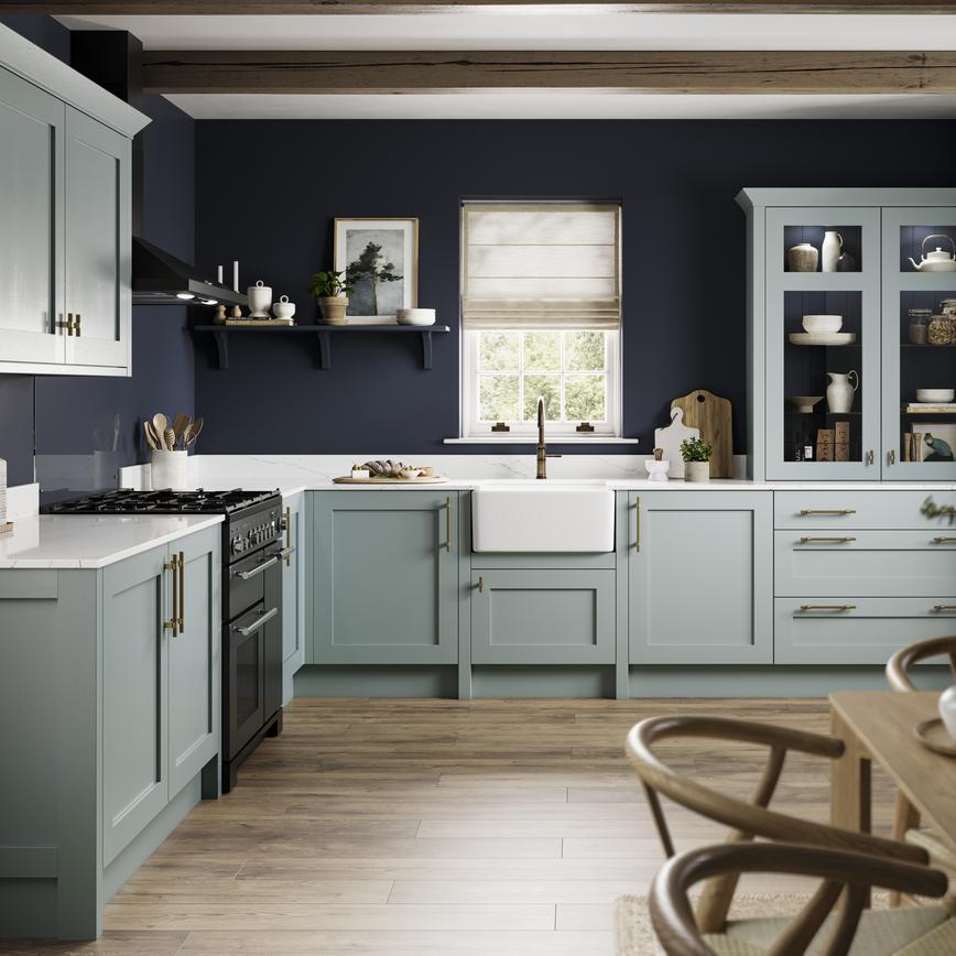 Seafoam blue shaker kitchen in an L-shaped layout. It features white worktops, wall mounted cabinets and brass accessories