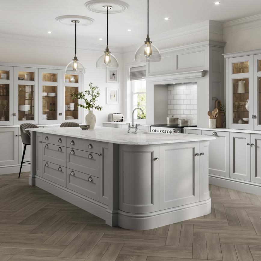 A stately kitchen featuring light-grey shaker doors with a beaded detail and glass dresser cabinets in an island layout.