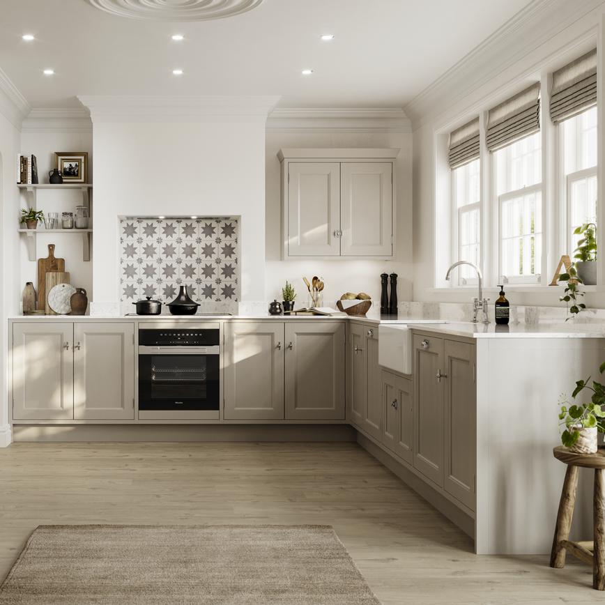 Cream in-frame shaker kitchen in an l-shape layout. Includes white worktops, a butler sink, and chrome decorative hinges.