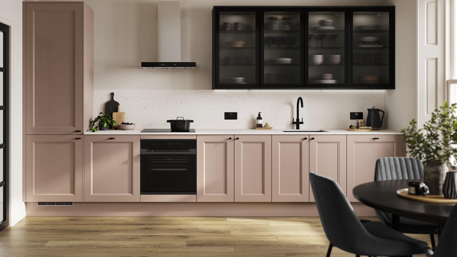 An antique-rose pink shaker kitchen in a single-wall layout. There are black glass wall cabinets and single-plank flooring.