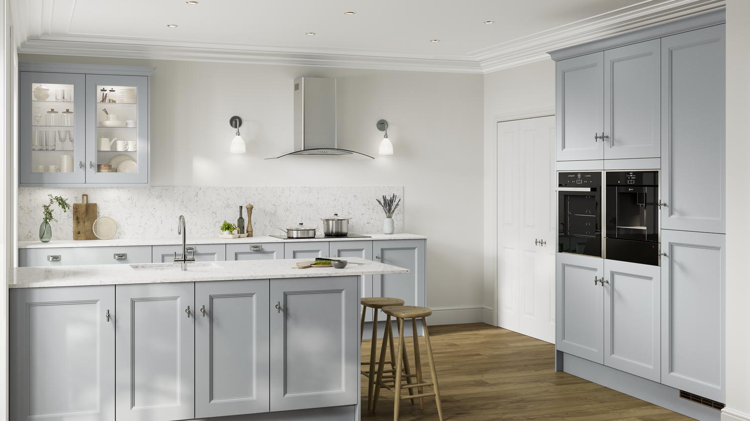 A peninsular kitchen, in a mist blue colour and shaker design. It has white worktops, black appliances, and glass wall units