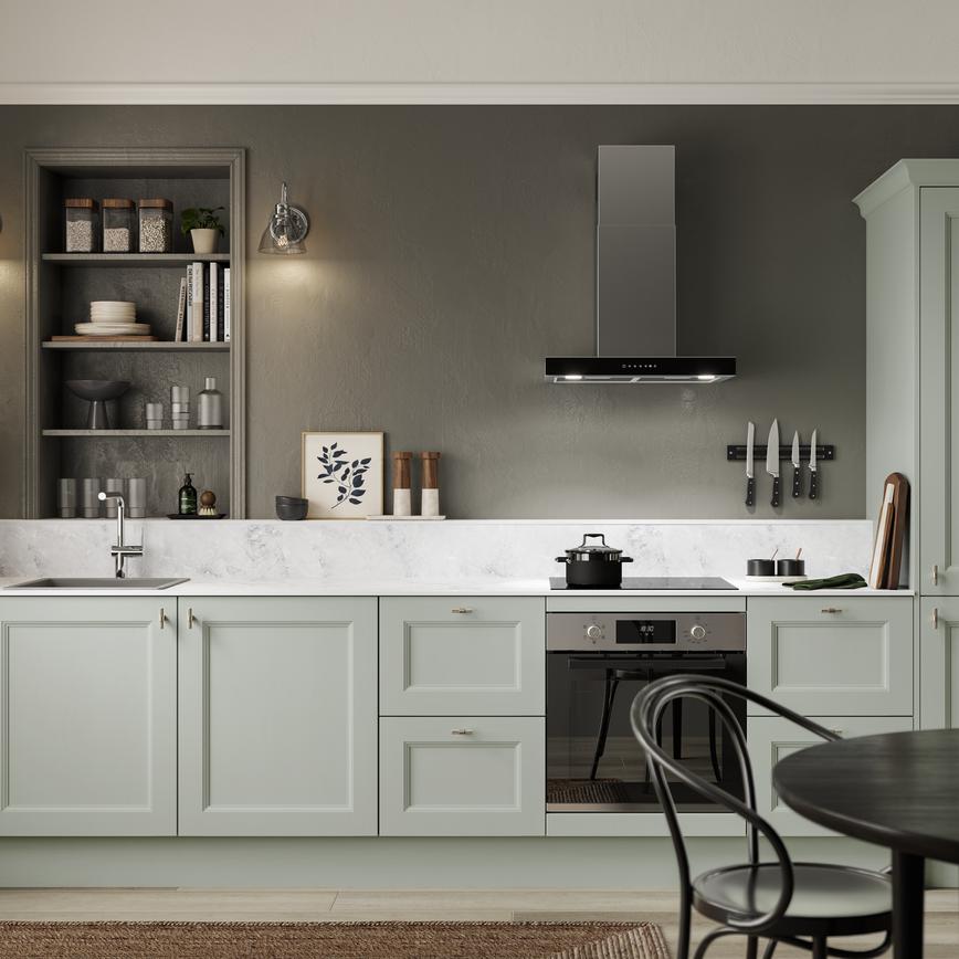 A pistachio green shaker kitchen in a single-wall layout. There is an integrated oven, white worktops and a white upstand