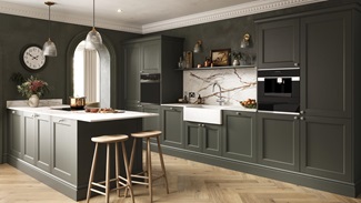 A dark-green kitchen with shaker doors in a single wall layout. It is styled with herringbone flooring and white worktops.