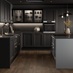 A black shaker kitchen in an L-shaped layout with a dusk blue island. There are black worktops and dark oak flooring.