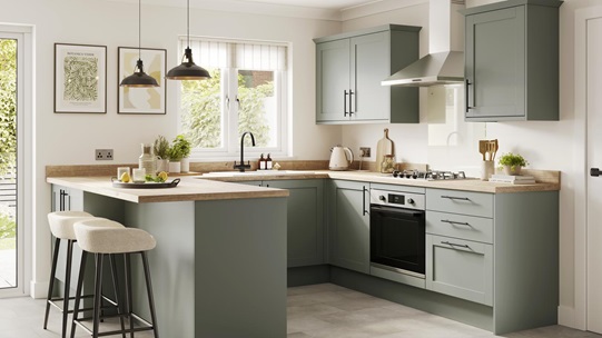 A light, reed green kitchen with shaker doors and bar handles. It is in a U-shaped layout and has timber worktops.