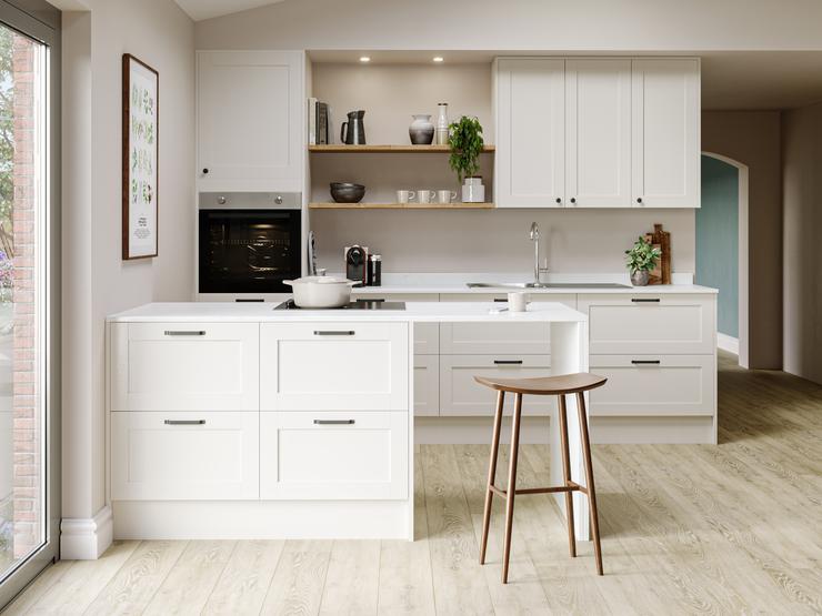 Subtle cream kitchen idea using antique white shaker doors and white worktops. Has a peninsular layout and a breakfast bar.