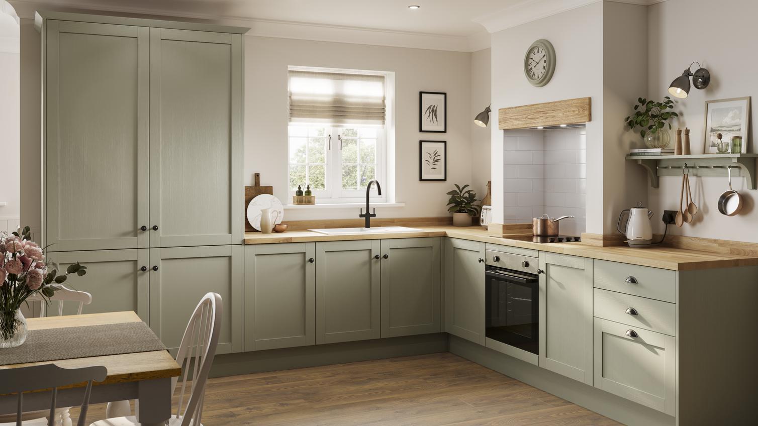 A country kitchen idea featuring sage-green, shaker cupboards in an L-shaped layout with wooden worktops and an electric hob.