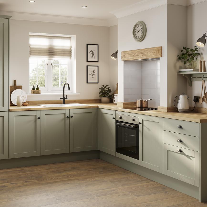 A country kitchen idea featuring sage-green, shaker cupboards in an L-shaped layout with wooden worktops and an electric hob.