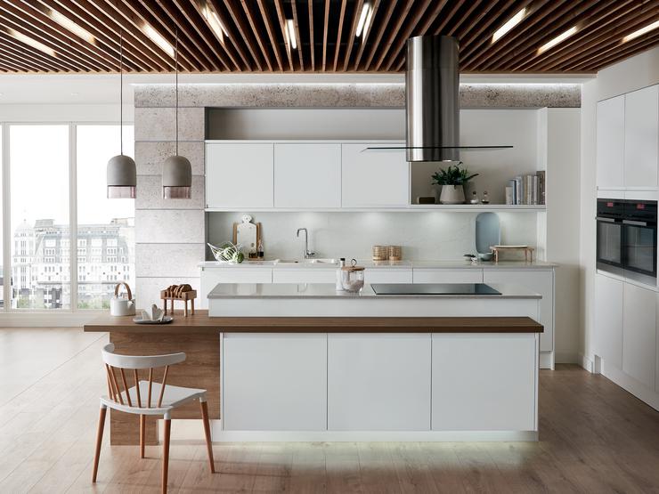 An open-plan Scandi white kitchen idea with super-matt handleless doors, a ceiling-mounted cooker hood, and a white sink.
