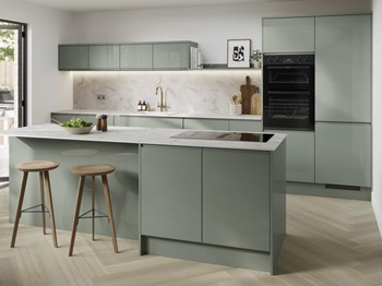 Gloss green kitchen with an island in the centre of the room. There are white marble-effect worktops and herringbone flooring