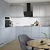 A blue kitchen from Clerkenwell Mist, in an l-shaped layout. It has a gloss finish, white wall cabinets & marble backboard.