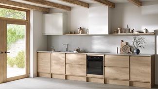 Natural oak kitchen from the Clerkenwell collection. It is in a single-wall layout with tiled flooring & white wall cabinets.
