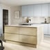 A pale, mist-blue kitchen with integrated handles. It has a kitchen island with oak-effect doors, and stone tile flooring.
