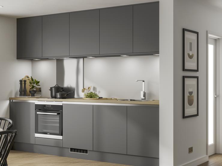 Handleless graphite grey kitchen along a single wall with built under electric oven and under cabinet led lighting.