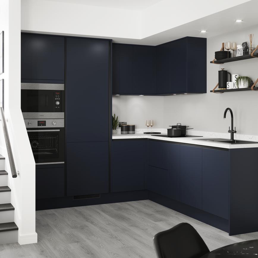 Handleless blue kitchen idea with navy doors and copper trims in an L-shaped layout. Has grey wood floors and white worktops.