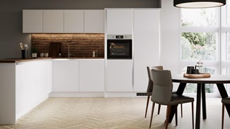 White handleless kitchen in an l shape with brick effect walls, wood worktop, chrome kitchen tap and round dining table.