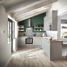 Grey kitchen design with slab, matt finish doors, in an L-shape with chrome kitchen cupboard handles and a breakfast bar.