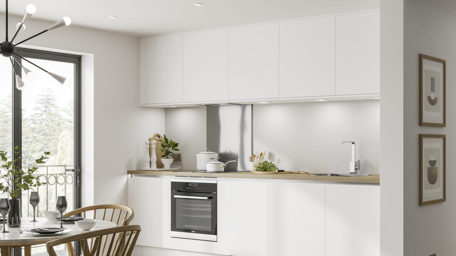 White matt handleless kitchen in single wall layout with under cabinet lighting, wood worktop and built under electric oven.