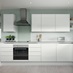 White l-shape kitchen with slab cupboards, white worktops, induction hob, and silver trims for an on-trend handleless look.