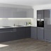 Slate grey handleless gloss kitchen in an l shape with contrasting white worktop, copper kitchen tap and built in oven.