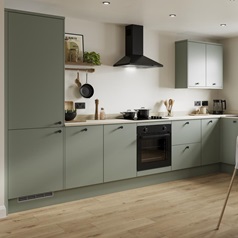 A modern green kitchen with cream worktops, black appliances and matching black accessories.