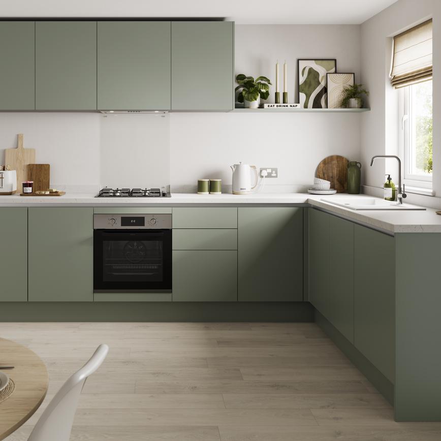 An l-shaped kitchen layout with green cabinets white marble-effect worktop, and pale wood flooring.
