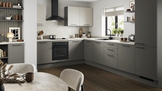 A modern green kitchen with cream worktops, black appliances and matching black accessories.