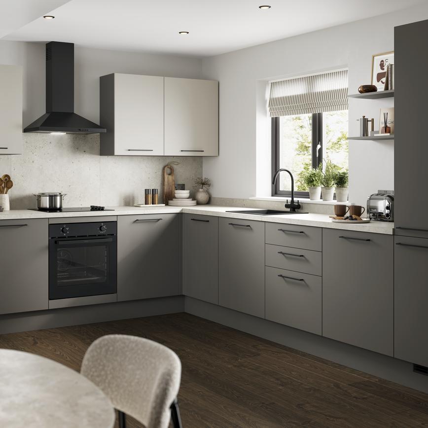 A modern green kitchen with cream worktops, black appliances and matching black accessories.