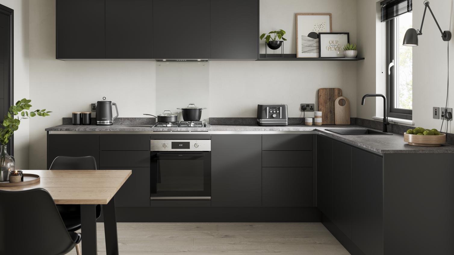 Sleek, modern black kitchen with handleless cabinetry, wall-mounted cupboards, and a grey worktop in an l-shape layout.