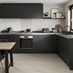 Sleek, modern black kitchen with handleless cabinetry, wall-mounted cupboards, and a grey worktop in an l-shape layout.
