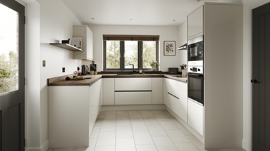 A porcelain, slab kitchen in a gloss finish and u-shaped layout. It has dark worktops, handleless doors and black profiles.
