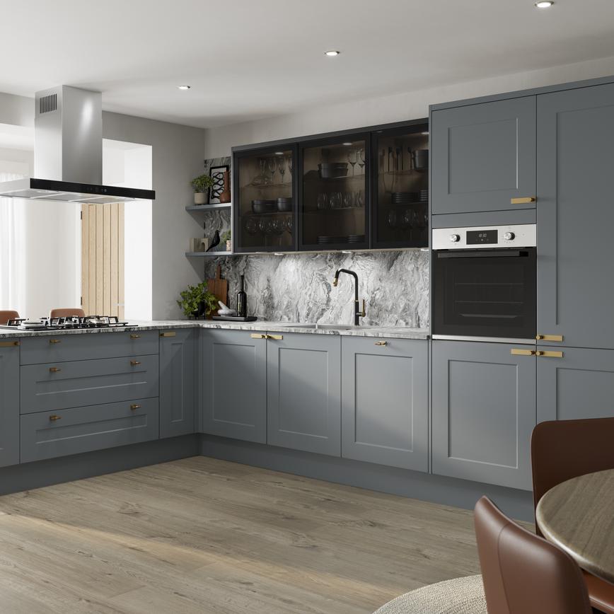 Blue kitchen with shaker doors in a l-shape layout. Contains marble worktops, black glass wall units, and aged brass handles.