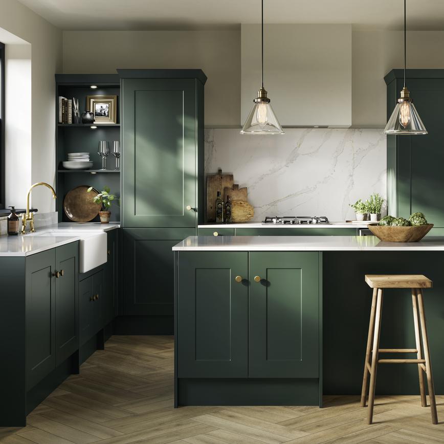 A fir green shaker kitchen idea in an island layout. Has white worktops, a ceramic sink, chevron flooring, and brass handles.