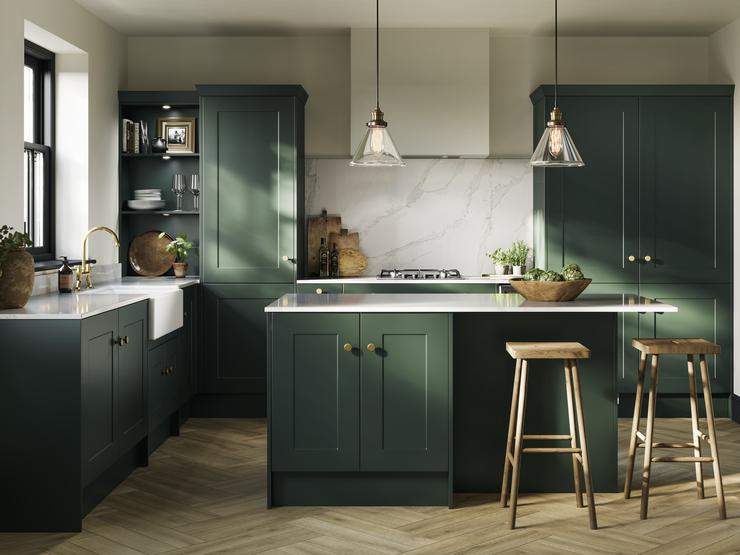 A fir green shaker kitchen idea in an island layout. Has white worktops, a ceramic sink, chevron flooring, and brass handles.