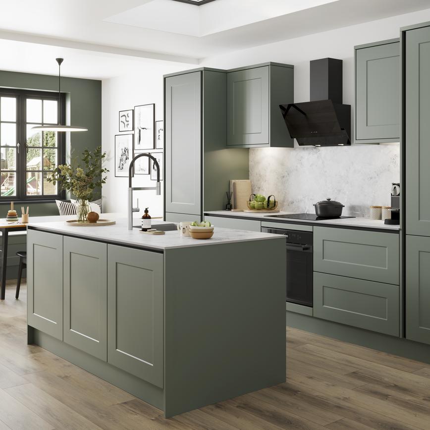A green kitchen with handleless cabinets and a kitchen island. Features a white worktop and matching backboard.