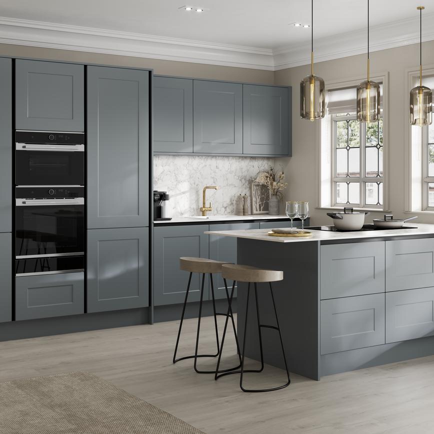 Handleless blue shaker kitchen with black trims in a peninsula layout. Contains a white breakfast bar and black double oven